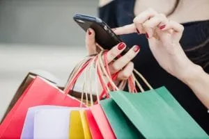 Woman with shopping bags holding smartphone